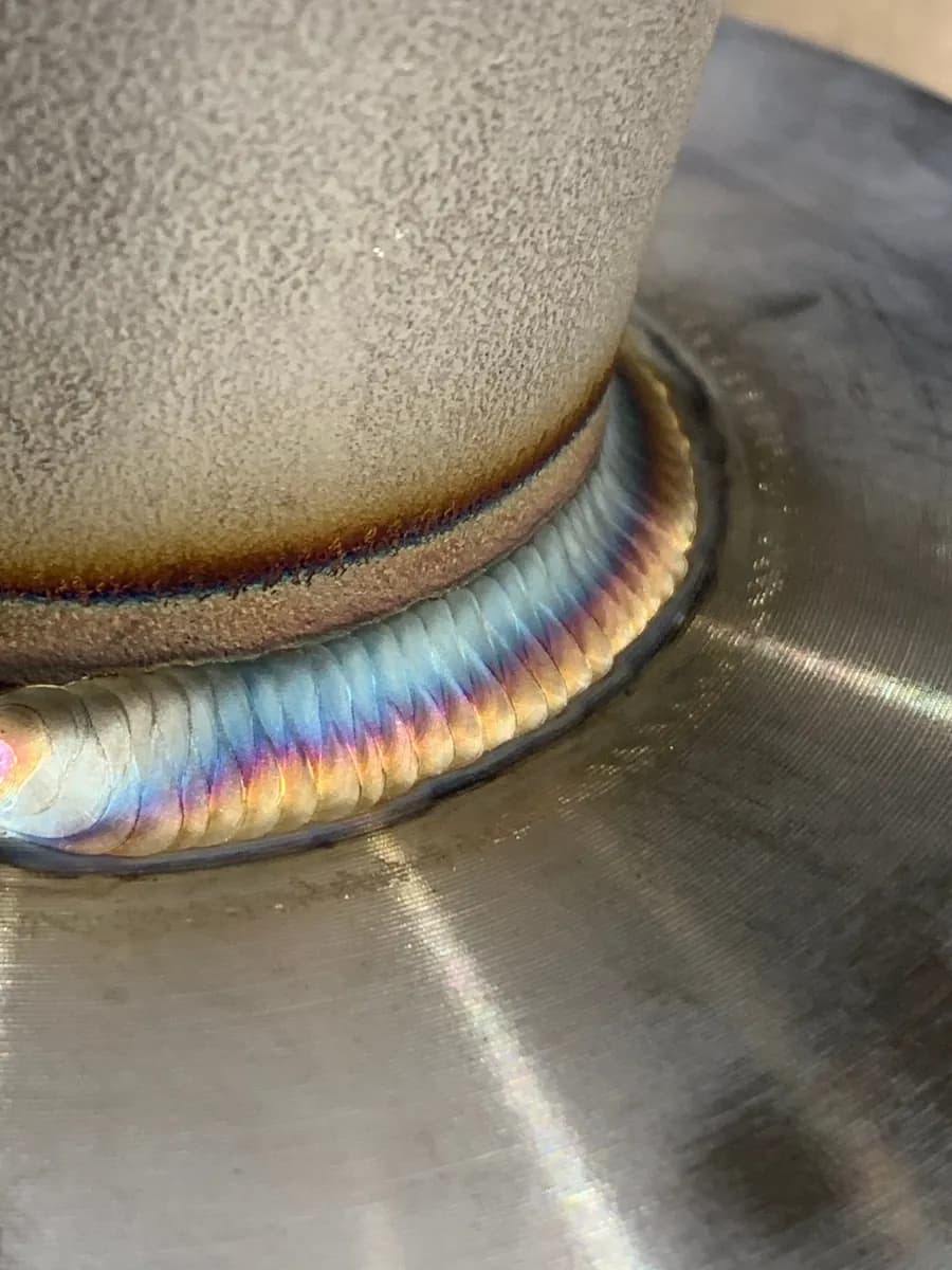 Nahaufnahme einer umlaufenden Metallnaht mit farbigen Anlaufspuren