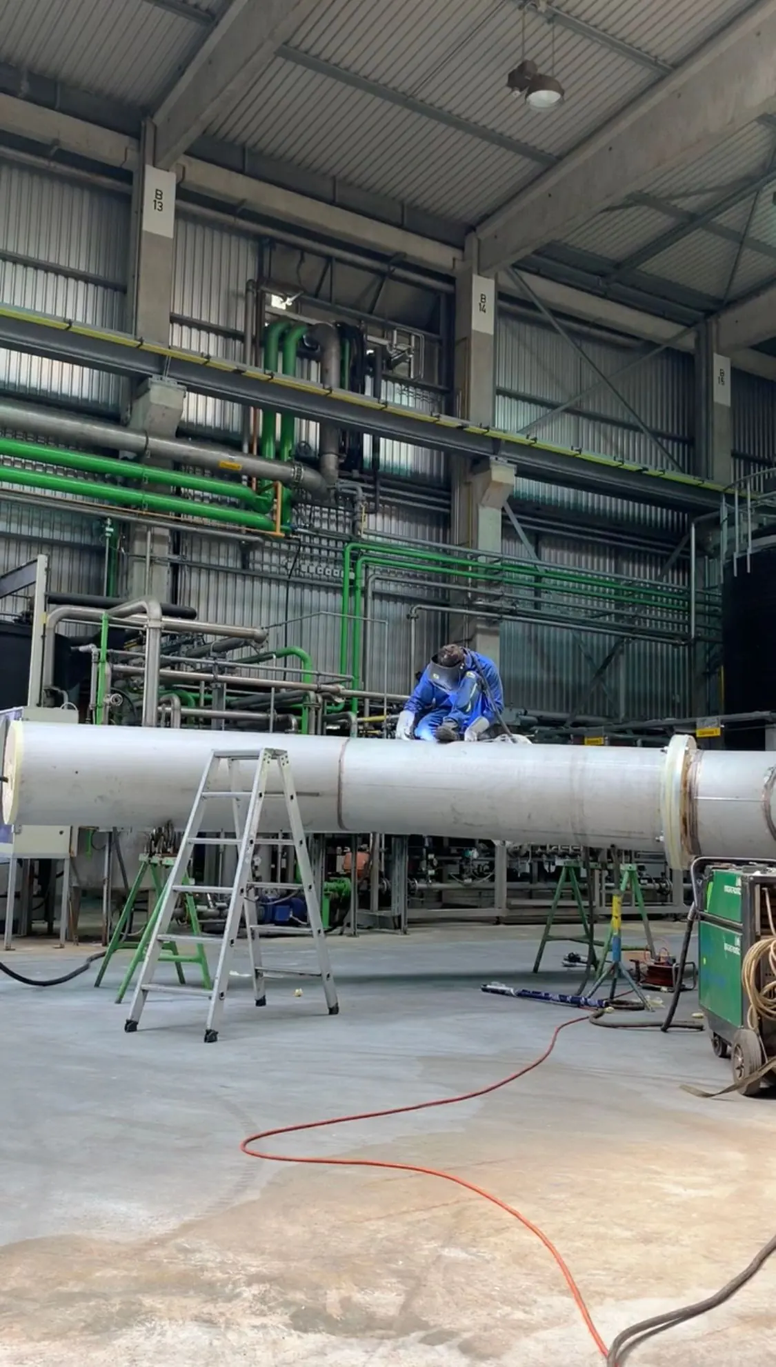 Mitarbeiter an einem großen Rohrbauteil in einer Werkhalle